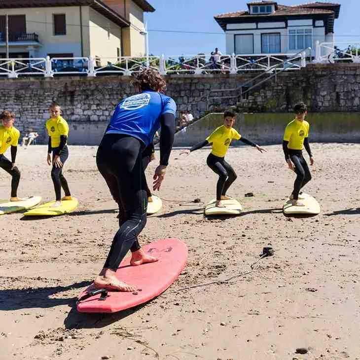 Clases de surf en la playa de Ribadesella, Asturias, con el Cantábrico al fondo